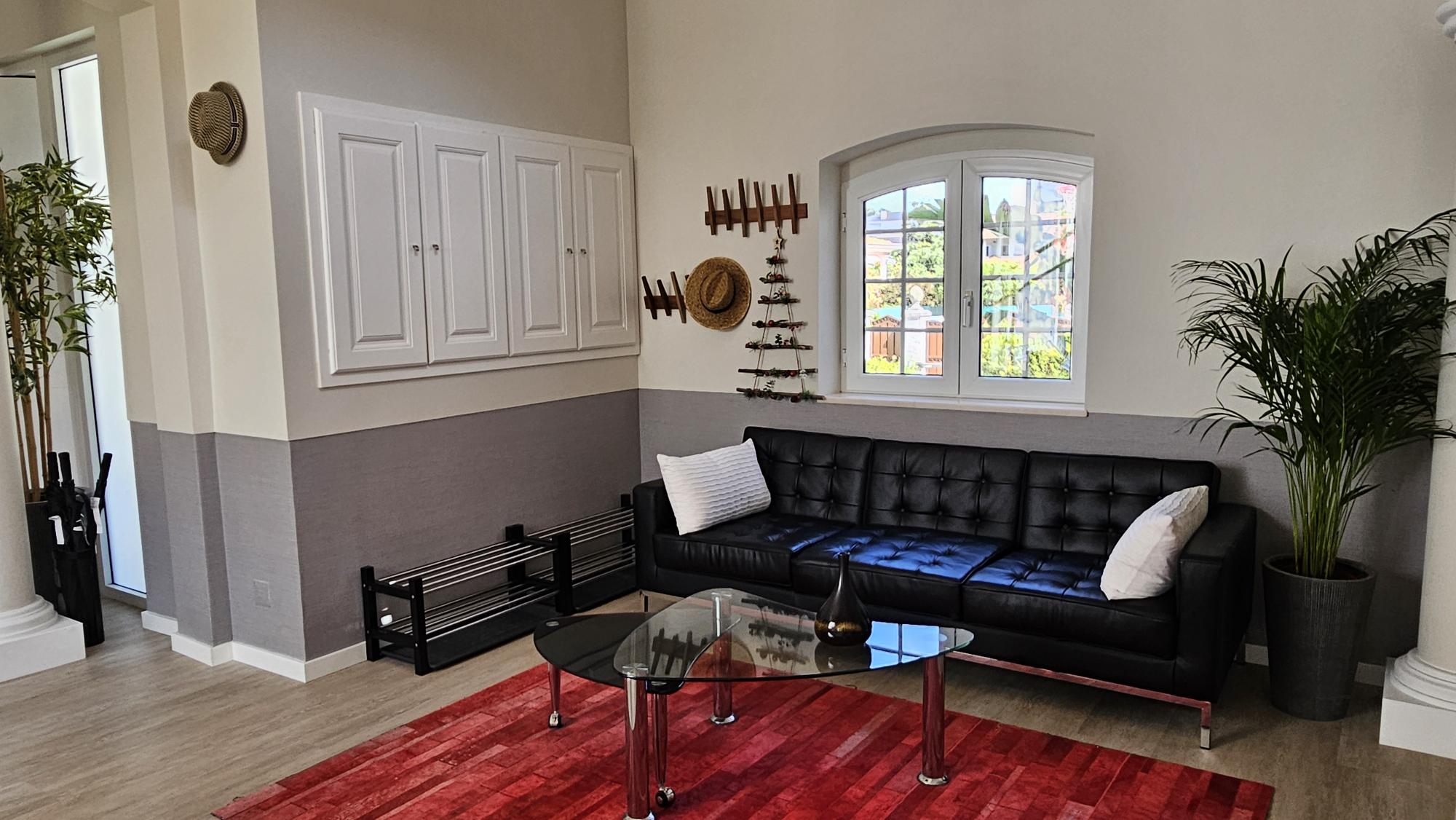 Black sofa, glass coffee table and garden window in the lounge at Cascais Vacation villa in Cascais, Portugal